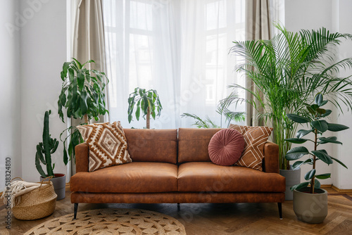 Brown sofa, potted green plants and wicker basket in room