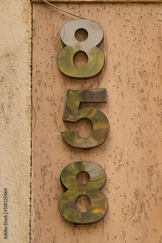 Número oitocentos e cinquenta e oito em metal pregado na parede de um prédio. 858. photo