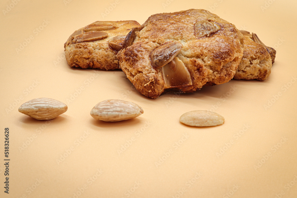homemade sweet almond cookies biscuits (amaretti) isolated on orange with three almonds