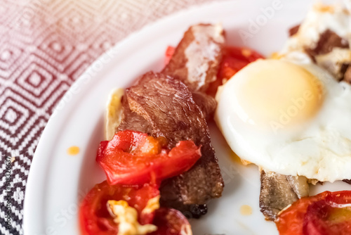 Fried eggs with pieces of beef and tomatoes. Close-up of delicious breakfast