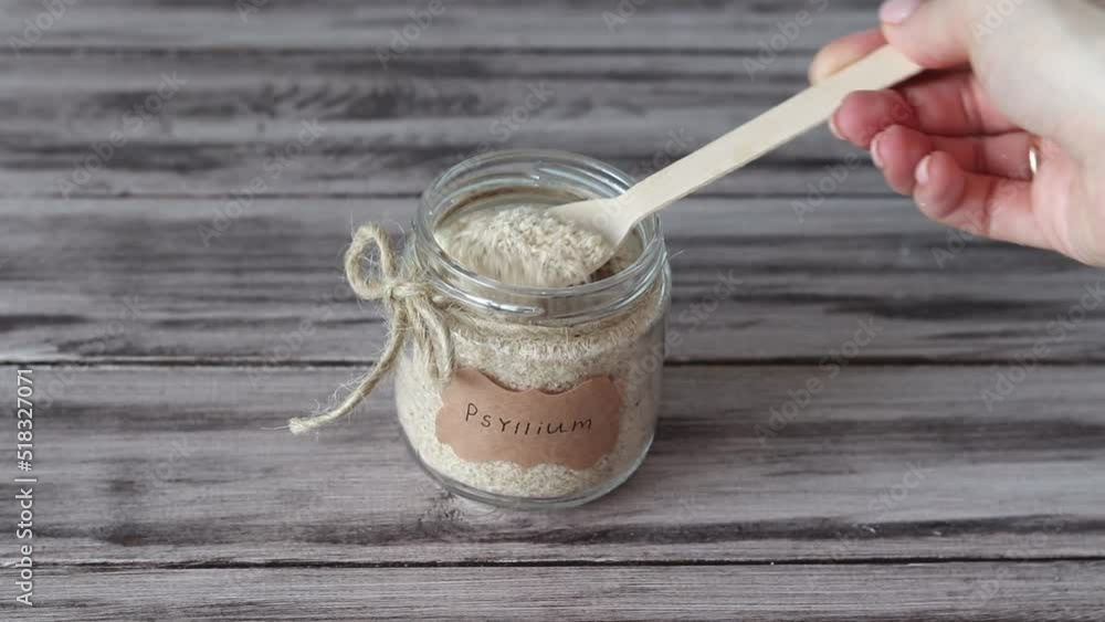 Psyllium is the husk of a plantain. Jar with a spoon and a sticker with the word Psyllium on a wooden background. Psyllium is the husk of a plantain. Jar with a spoon and a sticker with the word Psyllium on a wooden background.