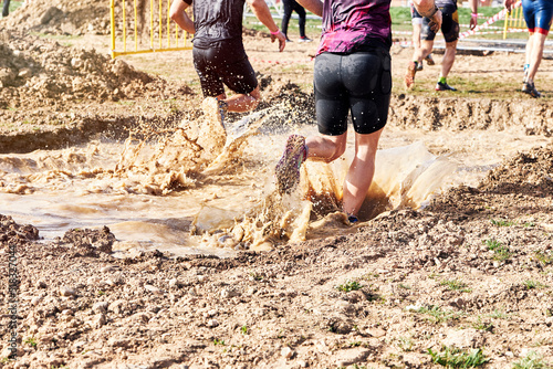 Group of participants in an obstacle course race running across a pool of water. Spartan race. Concept of hardness