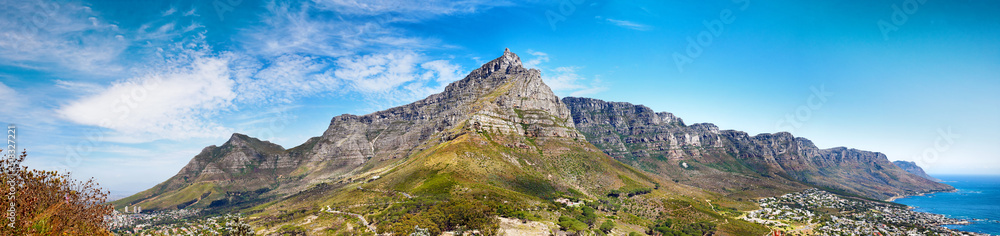 Panorama of Table Mountain and hills next to the ocean against a cloudy blue sky background with copy space. Scenic view of mother nature, sea and flora. The calm and beauty of mother nature