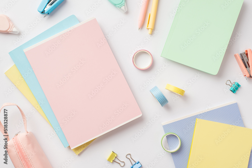 Back to school concept. Top view photo of notepads pens pencil-case mini staplers adhesive tape round correction tape and binder clips on isolated white background Back to school concept. Top view photo of notepads pens pencil-case mini staplers adhesive tape round correction tape and binder clips on isolated white background