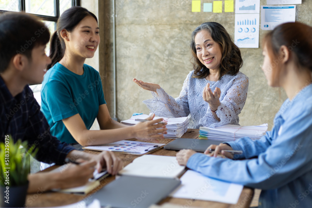 Group of young colleagues meeting with a senior female manager in the office to discuss their experience working on a company project. Group of young colleagues meeting with a senior female manager in the office to discuss their experience working on a company project.