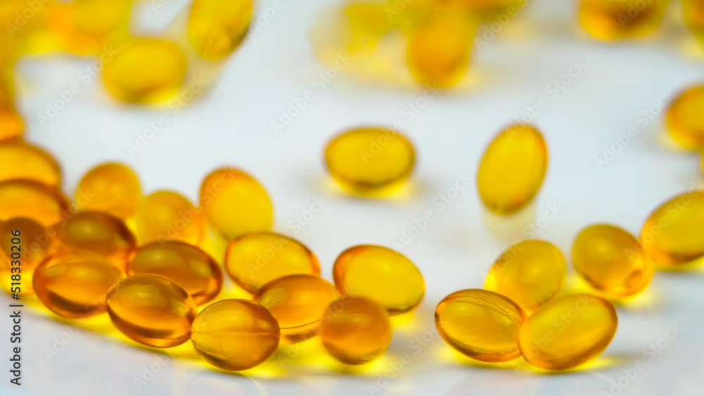 Fish Oil Capsules Rolling on a White Surface. Healthy Background and Medicine Concept. Omega 3 Natural Fat in Healthy Lifestyle and Sport Dieting. Yellow Pills with Cod Liver Oil Medicines Fish Oil Capsules Rolling on a White Surface. Healthy Background and Medicine Concept. Omega 3 Natural Fat in Healthy Lifestyle and Sport Dieting. Yellow Pills with Cod Liver Oil Medicines