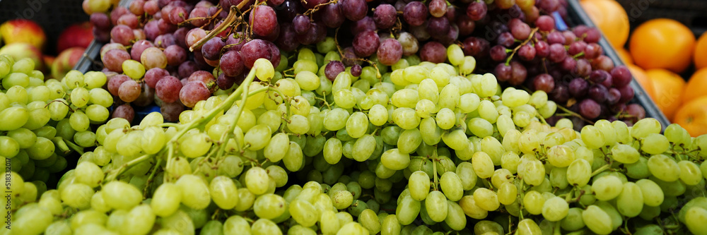 Heap of white and red grape fruit on public market counter. Fresh grape bunches at urban market place. Heap of white and red grape fruit on public market counter. Fresh grape bunches at urban market place.