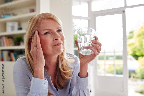 Photos Menopausal Mature Woman At Home Suffering With Headache Pain Drinking Glass Of W