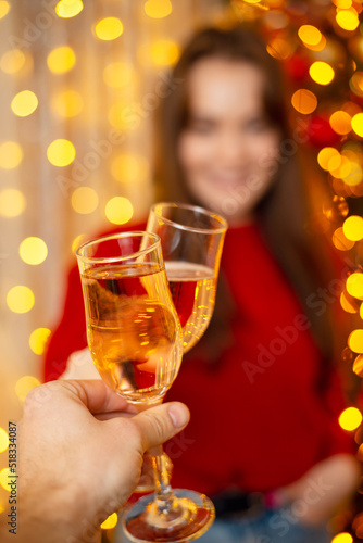 Two persons clink glasses full of champagne. New Years Eve, celebrating together with close friends and family, bright festive interior and mood