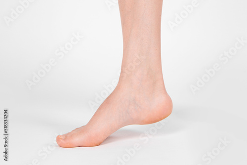 Barefoot and legs isolated on white background. Closeup shot of healthy beautiful female feet. Health and beauty concept. Side view of human foot ream with neutral manicure or pedicure. Sole of foot © mlphoto