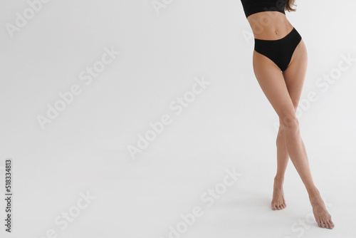 Tanned slim legs of a woman on white studio background. Close up of fitness model in sports clothing. Underpants or underwear advertising. Skin care or diet banner