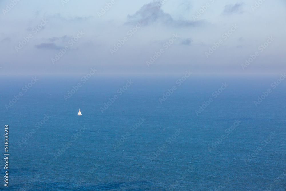 A view over the ocean off the Sussex coast with a sailing boat on the calm water
