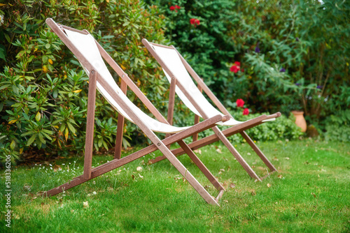 Two garden chairs on a lawn for a relaxing and quiet view of nature outside. Decorating and landscaping a park or natural environment with seats on grass. Lush plants in a peaceful backyard
