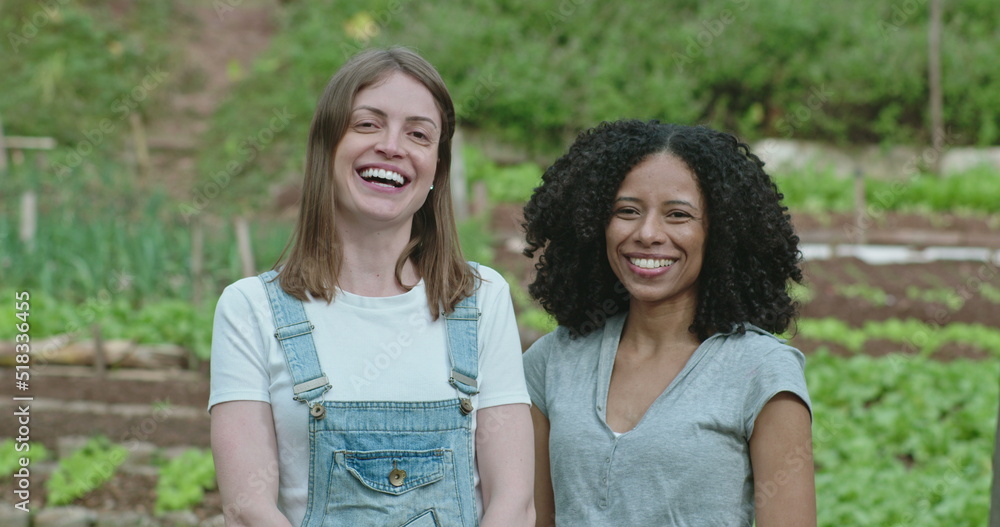 Portrait of two diverse women standing at community farm. young people at communitarian organic urban agriculture Portrait of two diverse women standing at community farm. young people at communitarian organic urban agriculture