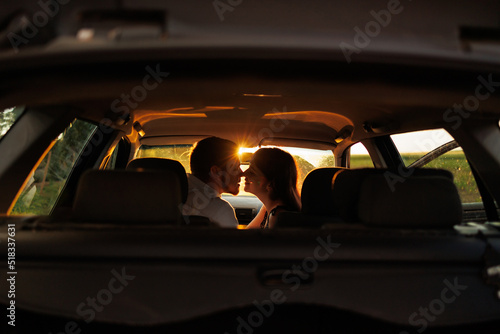 Romantic couple in sunlight from sunset kissing while sitting in car during trip © Andrii 