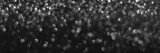 Gray black sparkling glitter bokeh background, christmas abstract defocused texture. Holiday lights. Snowy shiny sparkle stars header. Wide screen wallpaper. Panoramic web banner with copy space