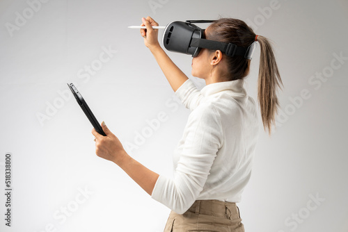 White shirt woman wearing VR glasses holding tablet and pen gesturing in the virtual world. © PIPAT