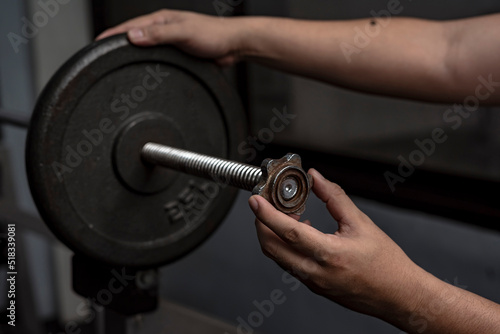 Securing a steel weight plate on a spinlock barbell bar with spinlock collars. Weightlifting and training safety concept photo