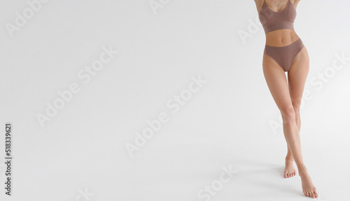 Tanned slim legs of a woman on white studio background. Close up of fitness model in sports clothing. Underpants or underwear advertising. Skin care or diet banner.