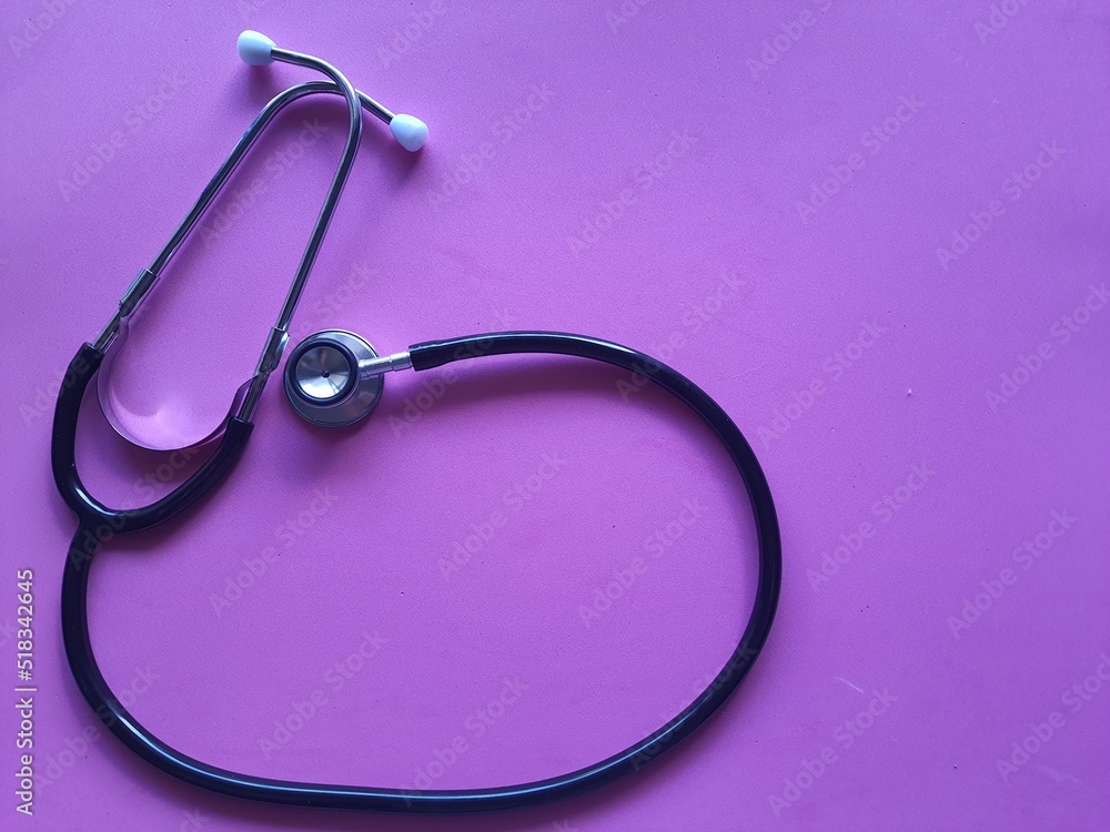 Fototapeta premium Stethoscope, isolated on a pink background, top view. Awareness of female diseases, breast cancer.