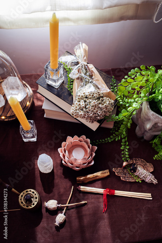 Altar with several books, plants, candles, semiprecious stones and matches tied with red thread..