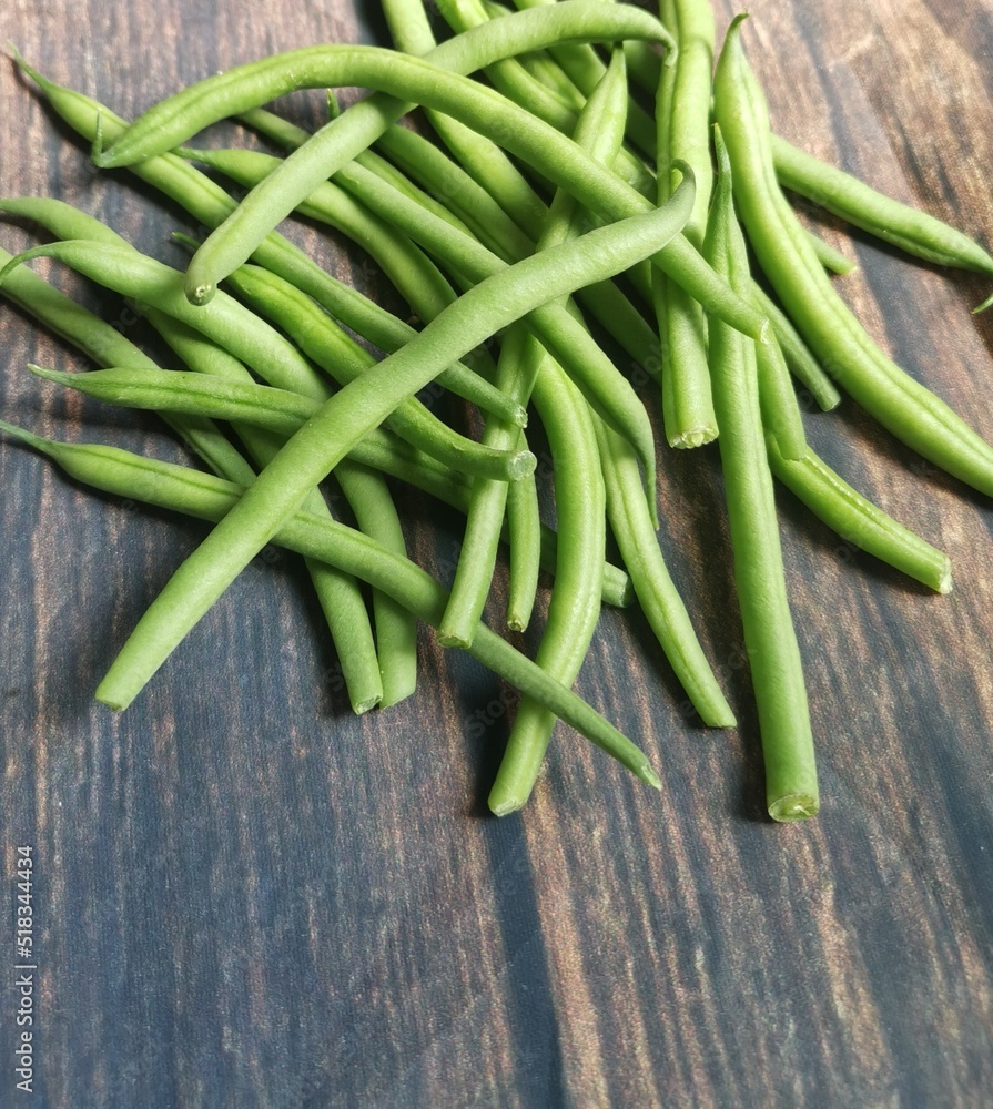 Pile of french beans lying on wooden rustic topped table Pile of french beans lying on wooden rustic topped table