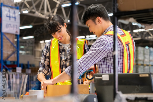 A man and women in charge of a large warehouse is checking the number of items in the warehouse that he is responsible for.