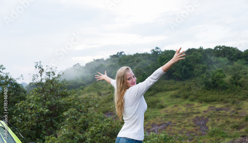 Happy of young woman rise her hands to the air near camping tent for camping outdoor on mountain