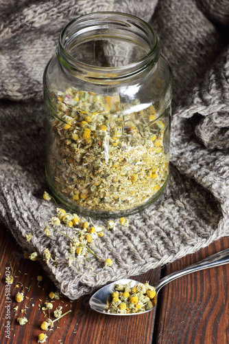 Schilderij op canvas Camomile herbal dried tea in a glass jar with flowers and knitted woolen sweater