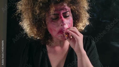 psychotic young woman with a dirty face smoking a joint in the throes of retching