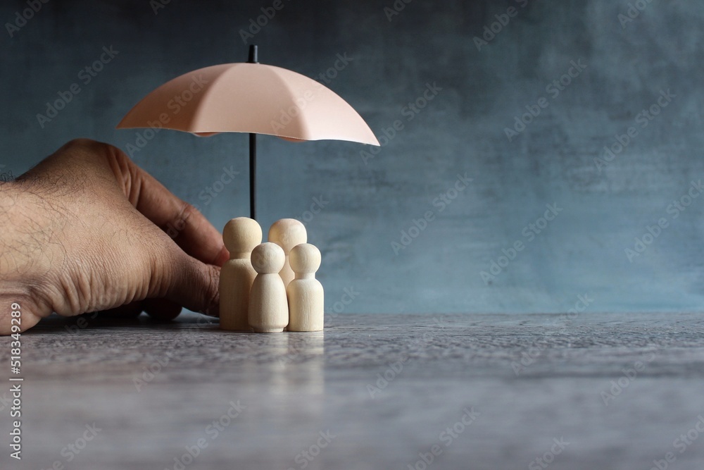 Umbrella and wooden dolls with copy space. Family protection and insurance coverage concept. - obrazy, fototapety, plakaty 