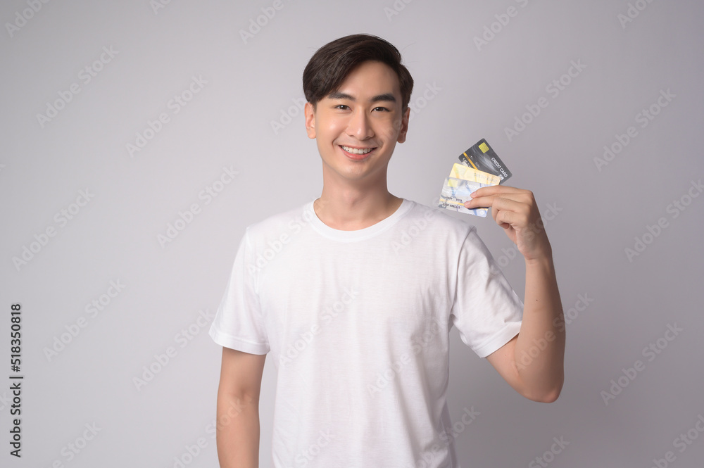 Young asian man holding credit card over white background studio, shopping and finance concept. Young asian man holding credit card over white background studio, shopping and finance concept.