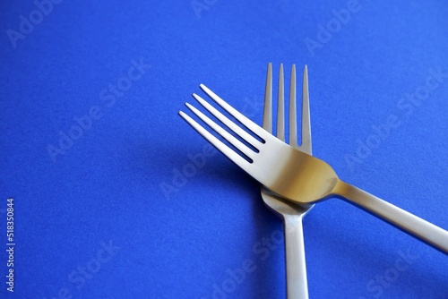 crossed silver forks on a blue tablecloth background
