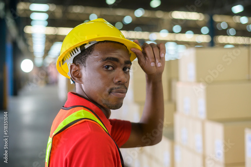 Portrait of young mixed race male worker wearing helmet in modern warehouse storage of retail shop photo