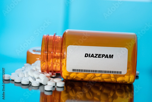 Diazepam white medical pills and tablets spilling out of a drug bottle. Macro top down view with copy space. photo