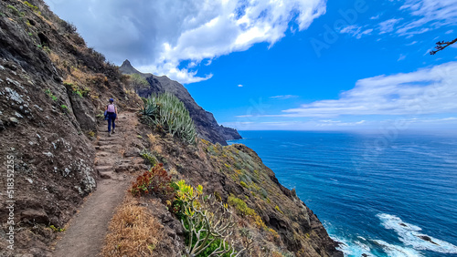 Backpack woman on hiking trail from Afur to Taganana with scenic view of Atlantic Ocean coastline and Anaga mountain range, Tenerife, Canary Islands, Spain, Europe. Looking at Cabezo el Tablero crag photo