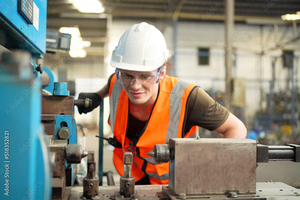 Young Caucasian hardworking heavy industry worker in protective suit and helmet using tablet and screwing valve. Young Caucasian hardworking heavy industry worker in protective suit and helmet using tablet and screwing valve.
