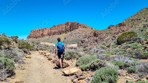 Man with backpack hiking to Riscos de la Fortaleza near Pico del Teide, Mount El Teide National Park, Tenerife, Canary Islands, Spain, Europe. Path via La Canada de los Guancheros dry desert plain photo