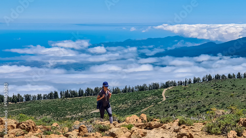 Woman on summit of Riscos de la Fortaleza with panoramic view on volcano Pico del Teide, Mount El Teide National Park, Tenerife, Canary Islands, Spain, Europe. Hike via La Canada de los Guancheros photo