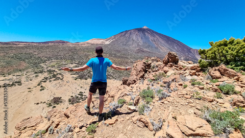 Sport man on summit of Riscos de la Fortaleza with panoramic view on volcano Pico del Teide, Mount El Teide National Park, Tenerife, Canary Islands, Spain, Europe. Hike via La Canada de los Guancheros photo