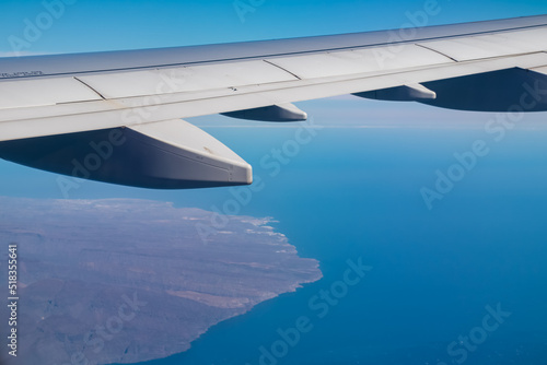 Aerial window view from an airplane on Gran Canaria, Canary Islands, Spain, Europe, EU. Wing and turbines of the aircraft can be seen. Flying high above the ground. Freedom. Flying into vacation