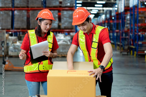 Asian two engineer in helmets team order details on document for checking goods and supplies on shelves with goods background in warehouse.logistic and business export