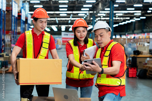Male Inventory Manager Shows Digital Tablet Information to a Worker Holding Cardboard Box, They Talk and Do Work. In the Background Stock of Parcels with Products Ready for Shipment.