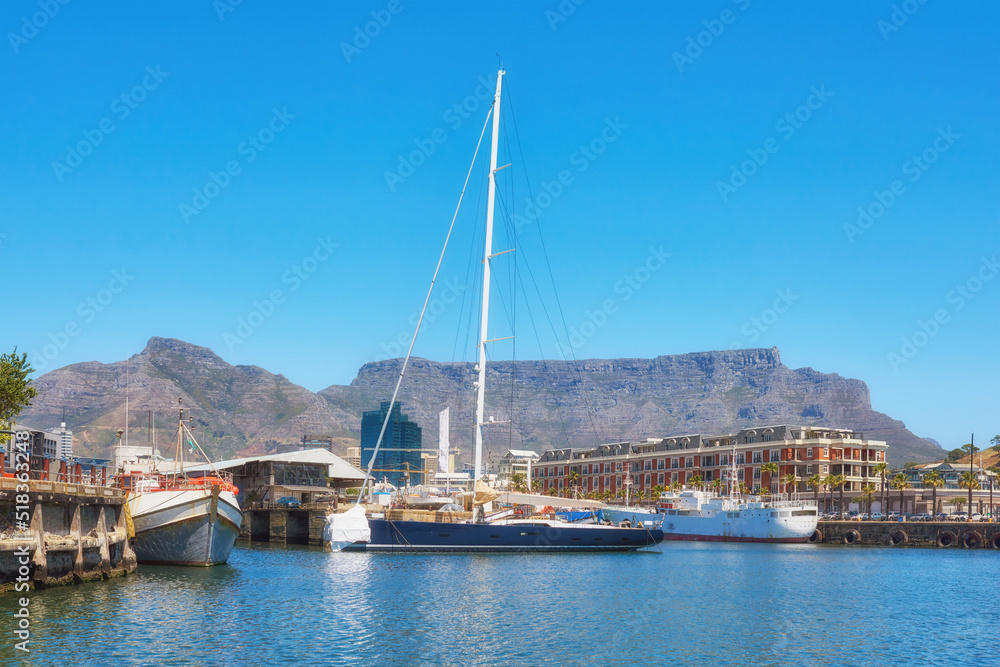 Sailboats docked at a harbor with Table Mountain in the background against blue sky with copy space. Scenic landscape of waterfront port at a marina dockyard. Nautical vessels for travel and tourism