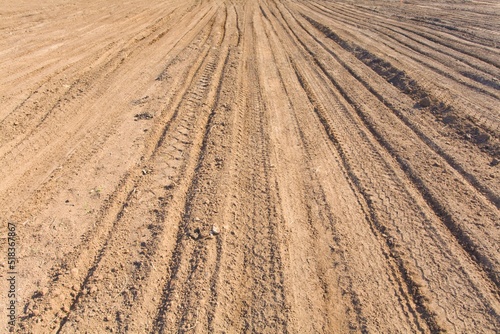 Texture brown yellow clay earth with traces of cars, trucks, tractors. Road with tire tracks.