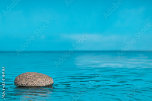 Zen-style minimalist composition. Stone in water with space for text. Blue color, copy space .