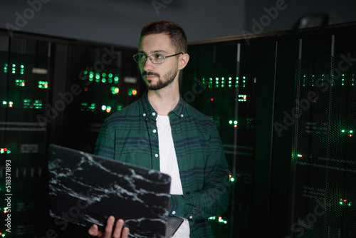 Skilled employee with laptop workig with DBMS hardware 