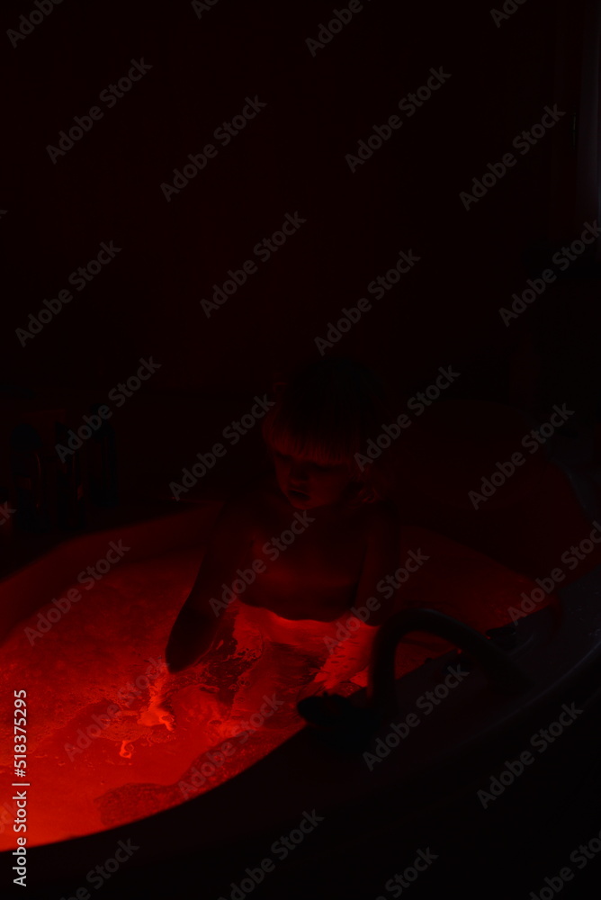 A little child taking a bath at night