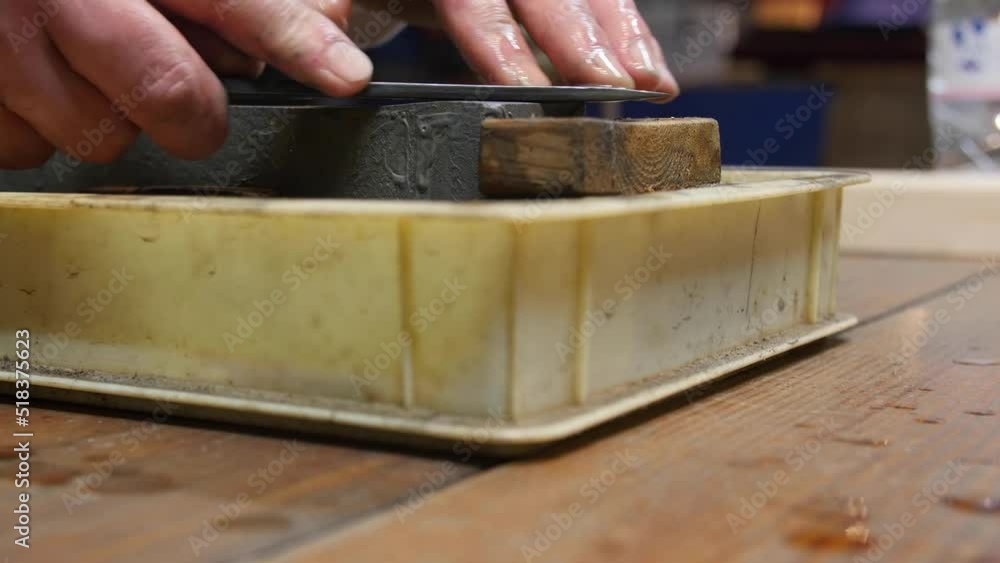 Master swordsmith is sharpening knife on grindstone with water Master swordsmith is sharpening knife on grindstone with water