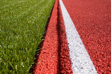 Sports stadium background. Red artificial rubber ground running tracks and white line and green synthetic artificial grass soccer sports field